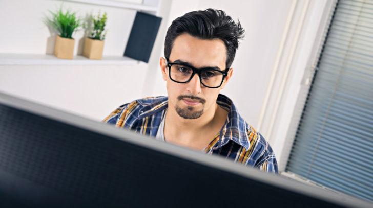 Joven con gafas frente a pantalla de PC