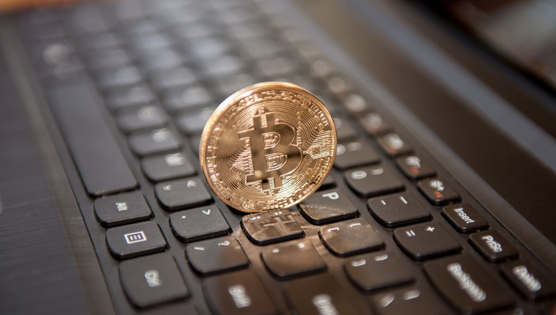 Moneda Bitcoin física sobre teclado negro